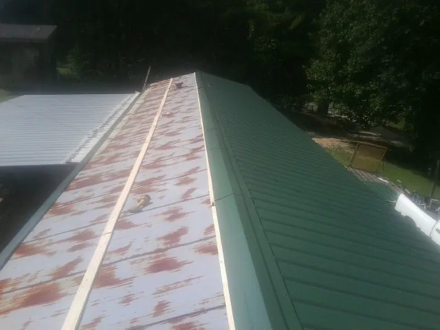 Old rusted panels beside newly installed green metal roofing — Wind Damage Roof Repair by Roofing Brothers in Cascade