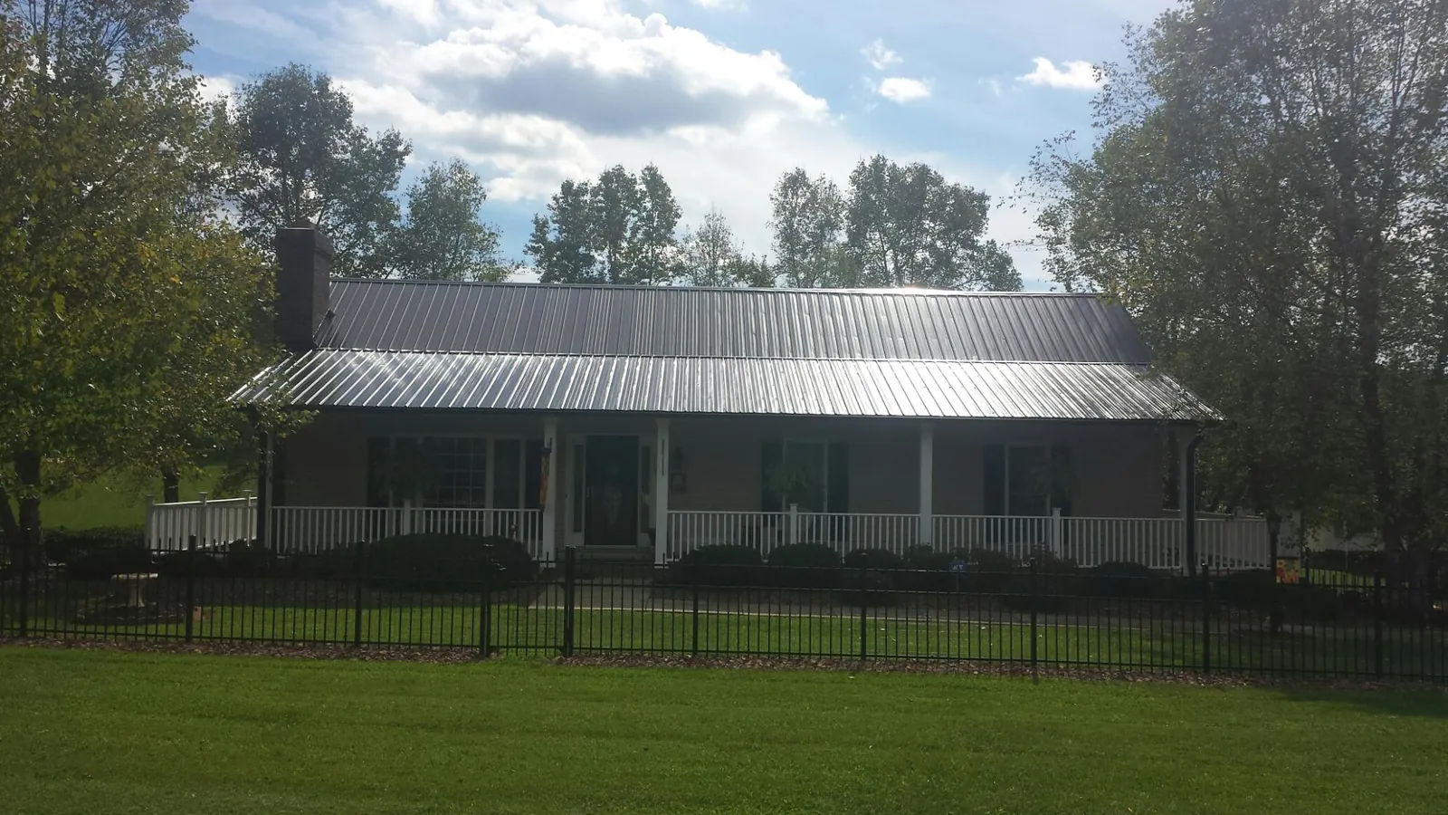 Gray metal roof on a brick ranch with a full width front porch — Gutter Guard Installation work by our crew in Cascade