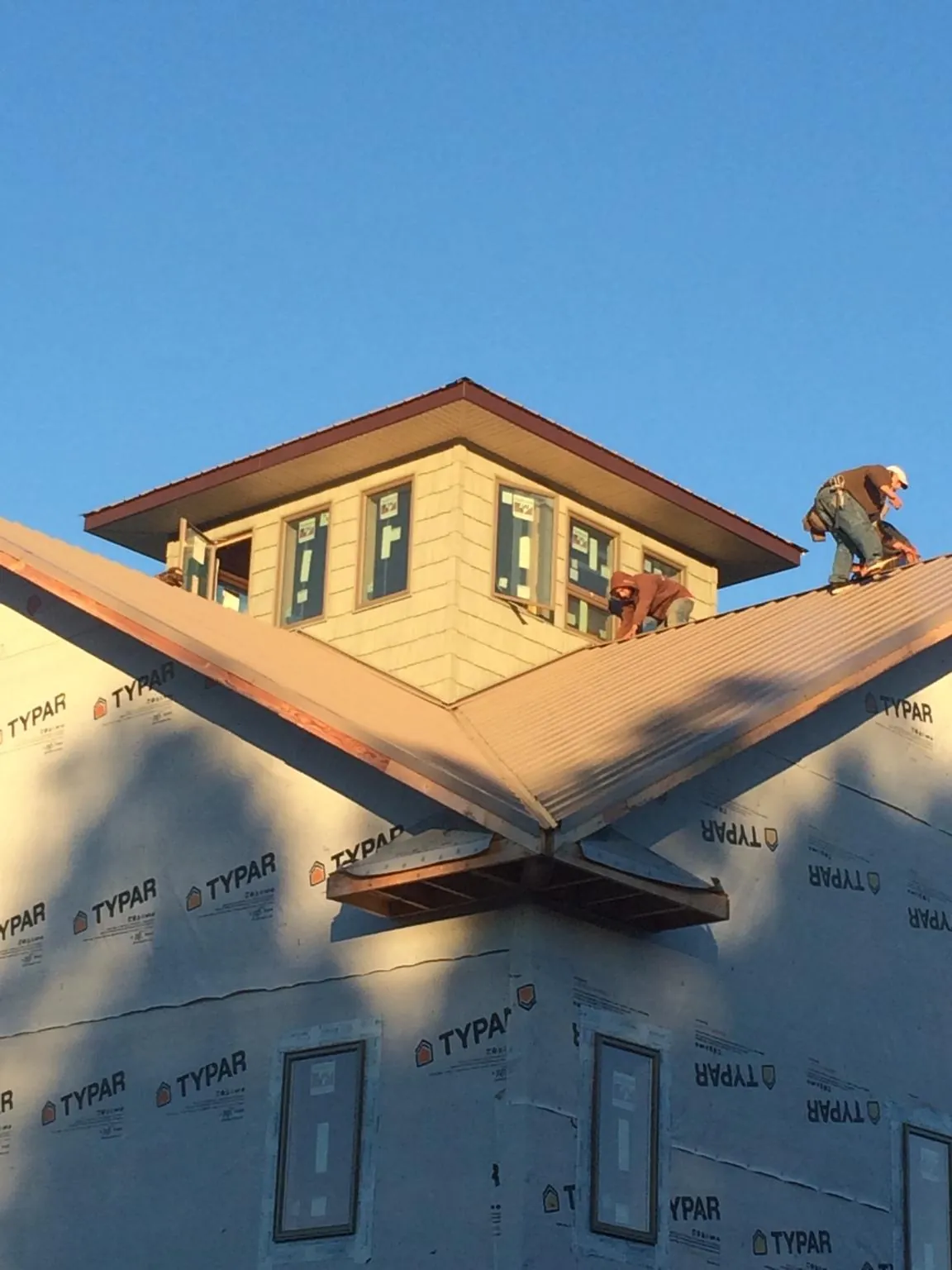 Roofers working around a rooftop cupola on a new metal roof at sunset — Roof Waterproofing in Cascade by Roofing Brothers